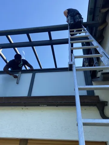 Reinigung eines Glasdachs von einer Leiter
